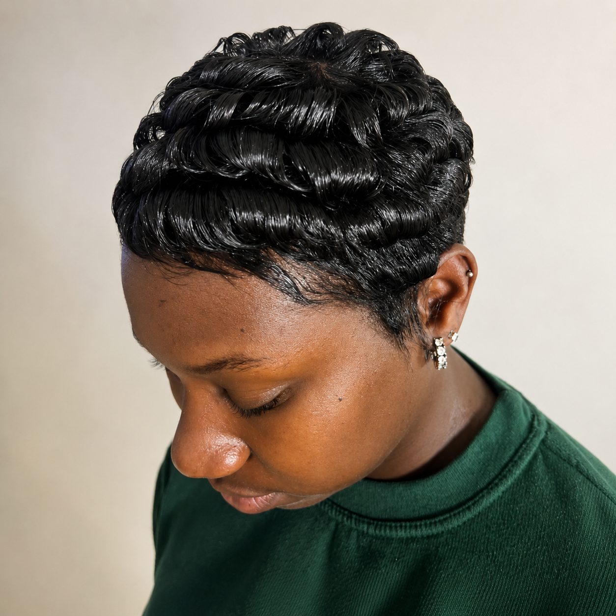 Top-down view of a freshly styled finger-wave pixie, client in a green sweater