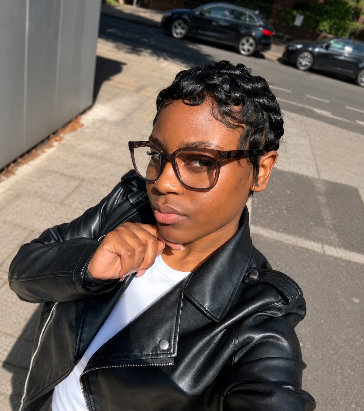 Client wearing a glossy finger-wave pixie cut, glasses and a black leather jacket on a South East London street